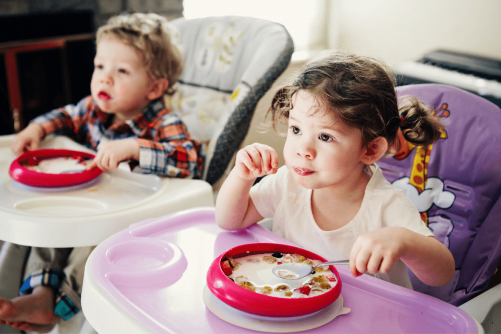małe dzieci jedzą posiłek wpatrując się w telewizor