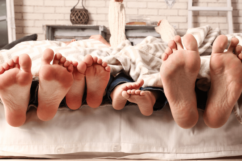 stopy rodziców i dzieci wystające spod kołdry