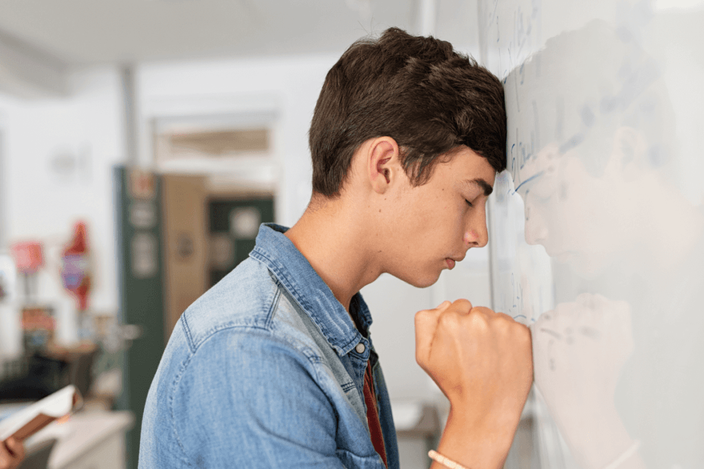 nastolatek opiera głowę o tablicę szkolną ukazując bezsilność, trudność w nauce